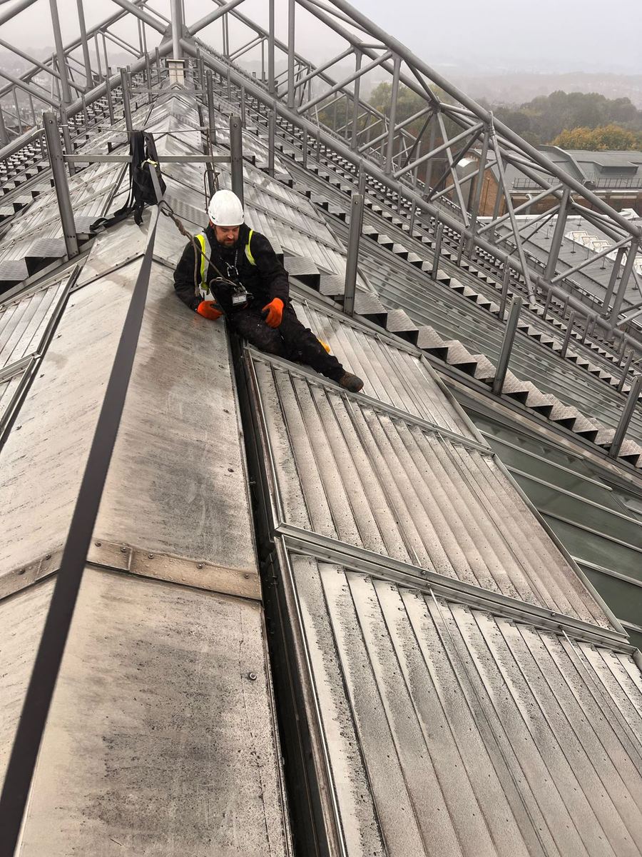 ARRT Group rope access operative in a hard hat and harness working beside the roof vents at Alexandra Palace
