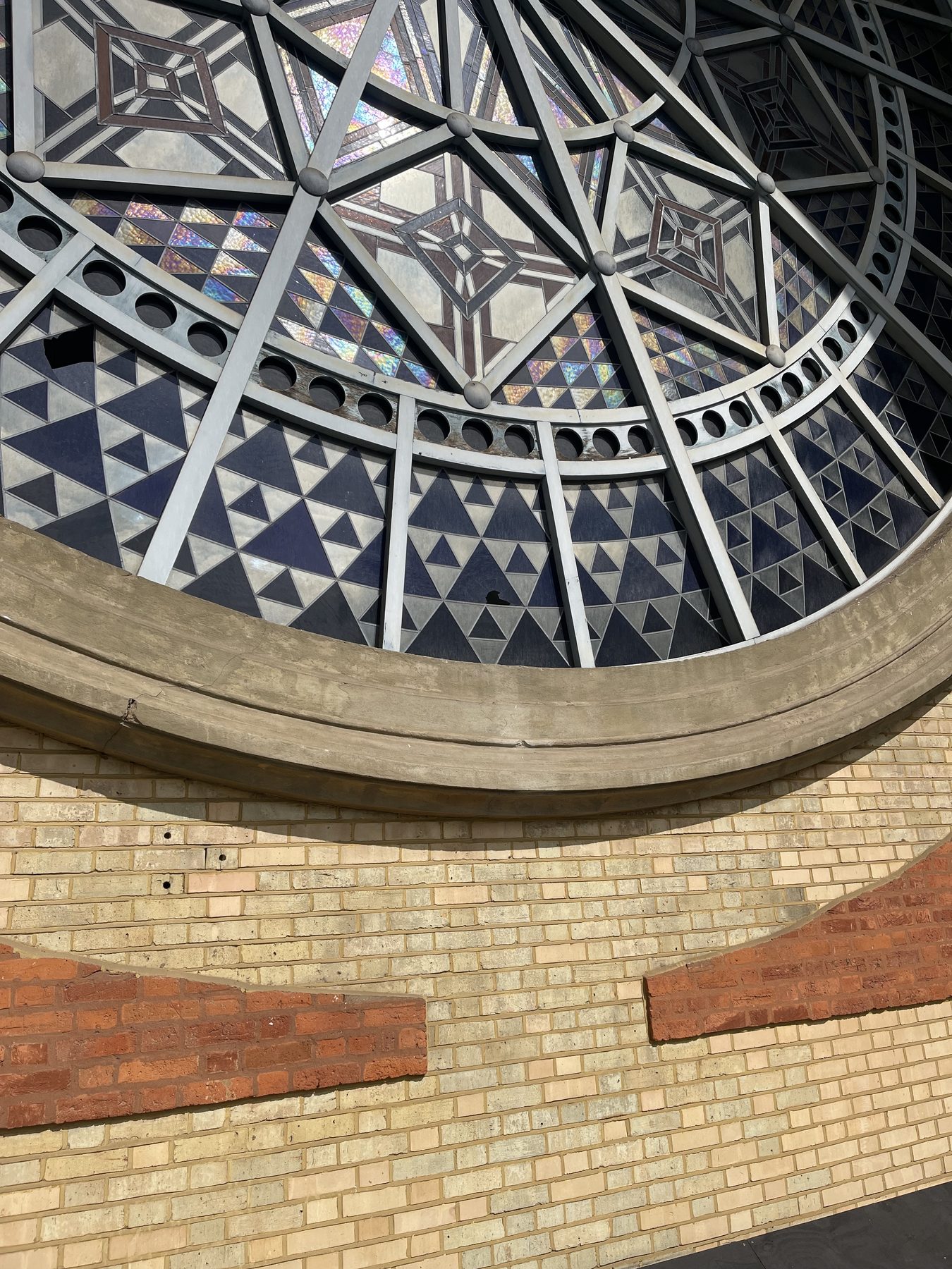 Circular stained glass rose window in tan brick at Alexandra Palace, Grade II listed