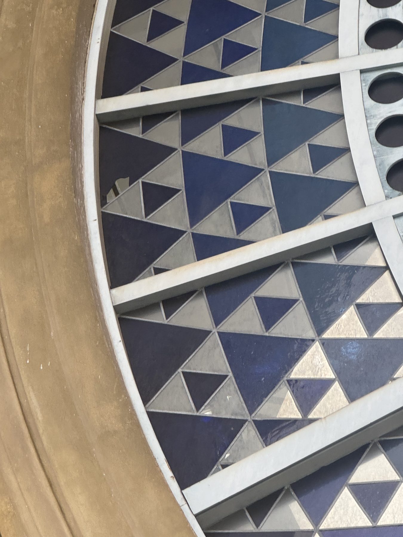 Close-up of geometric stained glass with a missing pane at Alexandra Palace