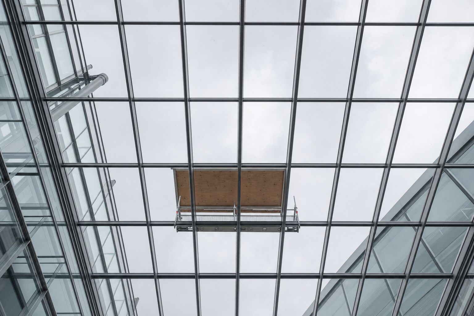 Overhead atrium glazing with steel glazing bars and a temporary crash deck below