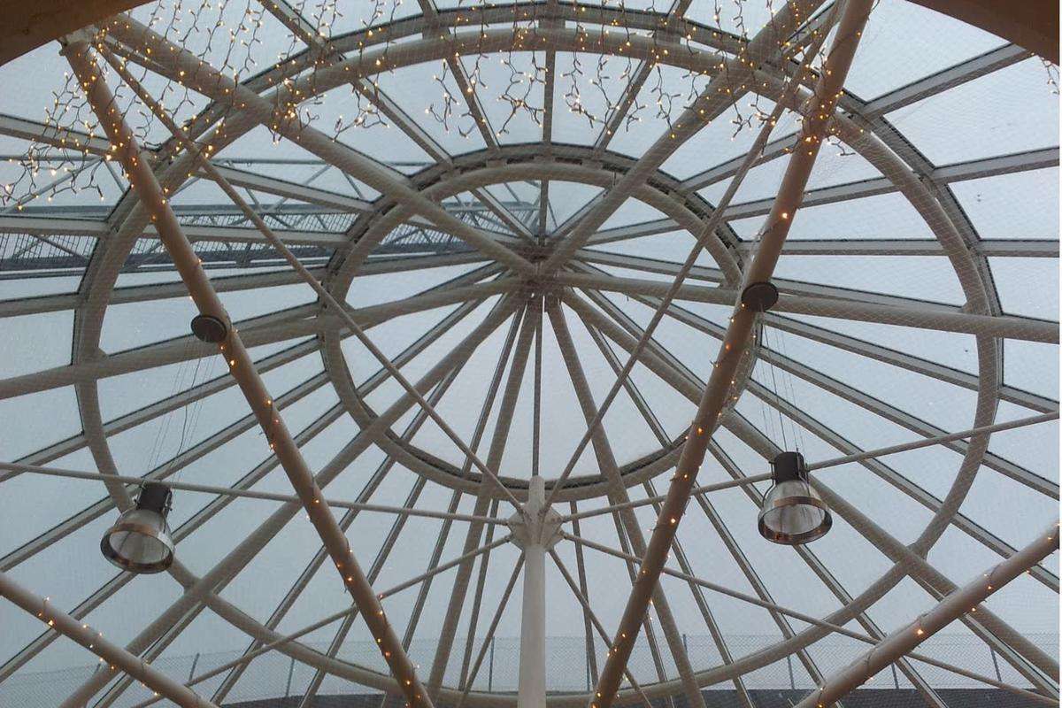 Looking up into a single glazed Victorian heritage glass roof dome with radiating steel glazing bars and suspended lights, during high-level roof glazing works